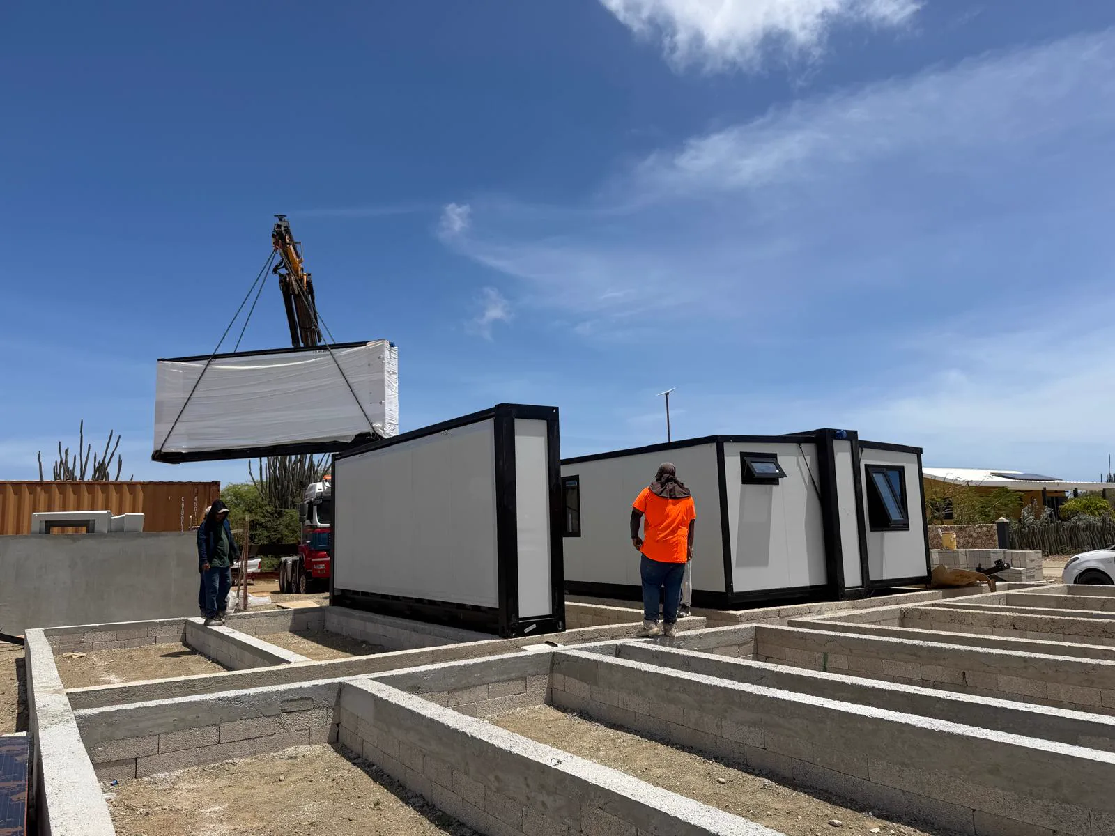 De kraan hijst een module boven de voorbereide fundering