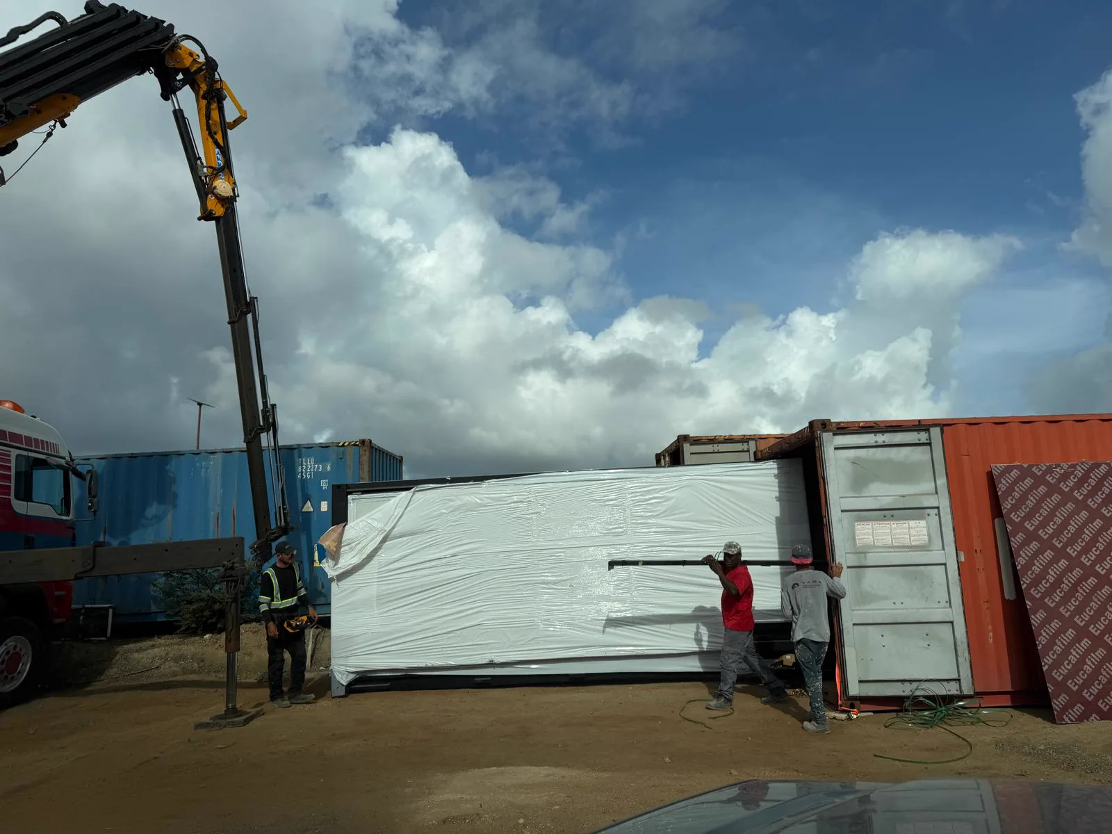 Een verpakte prefab module wordt uit de transportcontainer gehaald